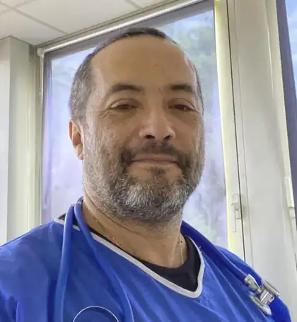 Dr. Alexandru-Theodor Amarfei wearing blue medical scrubs and a stethoscope